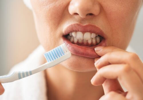 Woman’s gums showing irritation after tooth brushing too hard.